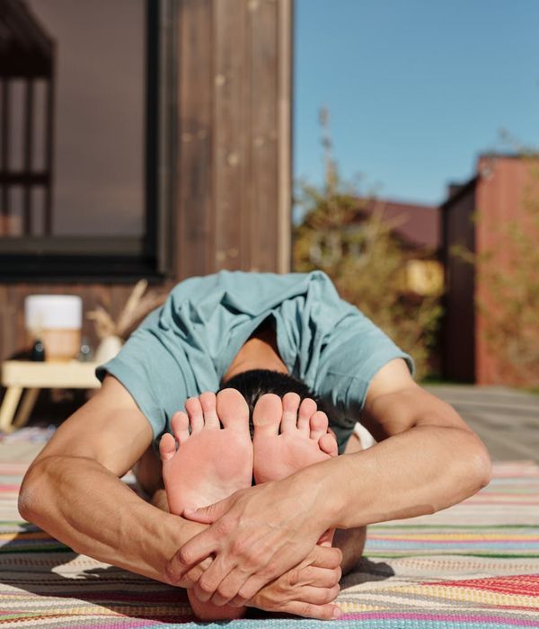 Man in a focused yoga pose, demonstrating balance and strength on a dark background.
